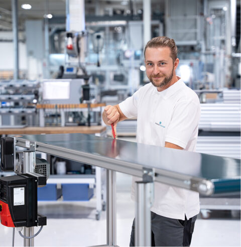 Ein lächelnder Robotunits-Mitarbeiter im weißen Poloshirt bei der Montage.